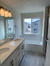 Bathroom with hardwood / wood-style flooring, vanity, a textured ceiling, and a washtub