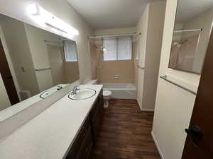 Full bathroom with vanity, tiled shower / bath combo, wood-type flooring, and toilet