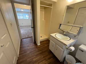 Bathroom with walk in shower, vanity, toilet, and hardwood / wood-style floors