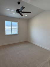 Carpeted empty room with ceiling fan and lofted ceiling