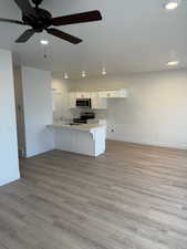 Kitchen featuring sink, appliances with stainless steel finishes, white cabinetry, light hardwood / wood-style floors, and kitchen peninsula