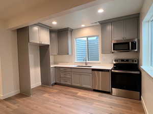 Kitchen featuring stainless steel appliances, light hardwood / wood-style floors, sink, and gray cabinetry