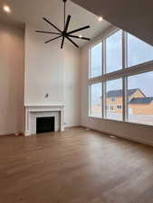 Unfurnished living room with wood-type flooring and a high ceiling