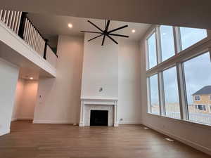 Unfurnished living room with hardwood / wood-style flooring and a towering ceiling