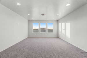 Empty room with carpet and a textured ceiling