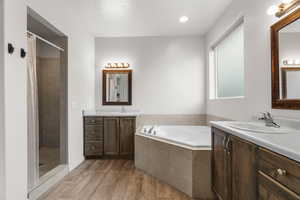 Bathroom with wood-type flooring, separate shower and tub, and vanity