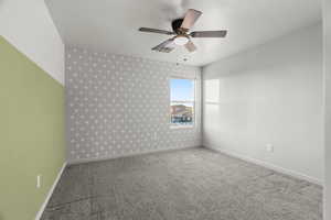 Unfurnished room featuring ceiling fan, a textured ceiling, and carpet flooring