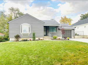 View of front of property featuring a garage and a front lawn