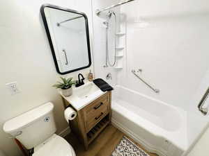 Full bathroom with vanity, hardwood / wood-style floors, tiled shower / bath, and toilet