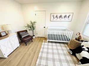 Bedroom with light wood-type flooring and a crib