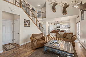 Living room with hardwood / wood-style flooring, a towering ceiling, and an inviting chandelier