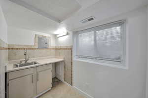 Bathroom with tile walls, vanity, electric panel, tile patterned floors, and a textured ceiling