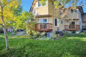 Rear view of property with a wooden deck, a yard, and central air condition unit