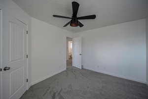 Unfurnished bedroom with ceiling fan, carpet floors, and a textured ceiling