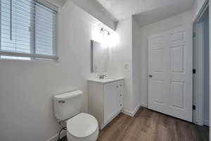 Bathroom featuring hardwood / wood-style flooring, vanity, toilet, and a textured ceiling