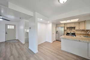 Kitchen with tasteful backsplash, sink, light wood-type flooring, stainless steel appliances, and a textured ceiling