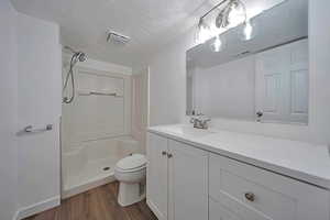 Bathroom featuring a shower, hardwood / wood-style flooring, vanity, toilet, and a textured ceiling