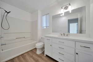 Full bathroom with hardwood / wood-style flooring, vanity, toilet, and shower / bath combination