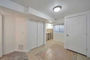 Interior space with connected bathroom, a textured ceiling, and light tile patterned floors