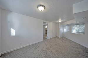 Carpeted spare room featuring a textured ceiling