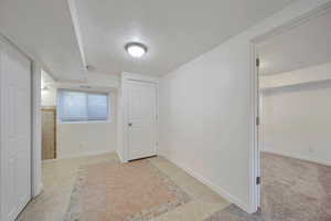 Corridor with light tile patterned floors and a textured ceiling