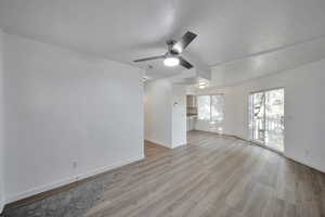 Unfurnished living room featuring ceiling fan, a textured ceiling, and light wood-type flooring