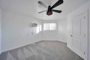 Empty room with ceiling fan, carpet, a textured ceiling, and an AC wall unit