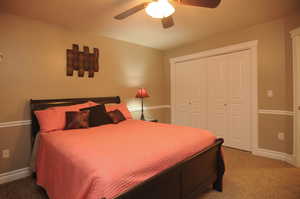 Carpeted bedroom featuring a closet and ceiling fan