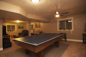 Playroom with ceiling fan, carpet, and a textured ceiling