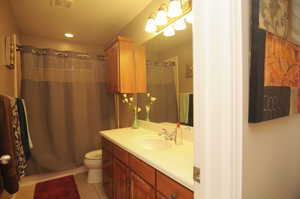 Bathroom with a shower with curtain, tile patterned floors, toilet, and vanity