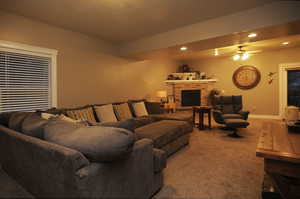 Living room featuring a fireplace, carpet floors, and ceiling fan