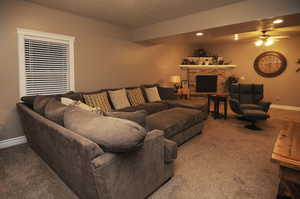 Carpeted living room featuring ceiling fan and a fireplace