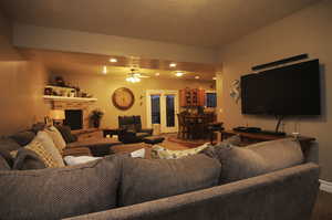 Carpeted living room with an outdoor brick fireplace and ceiling fan