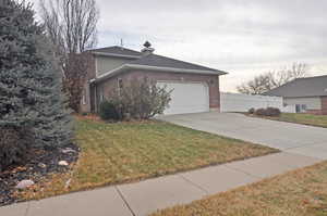 View of side of property with a garage and a lawn