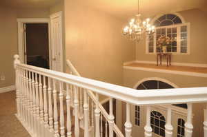 Hall featuring an inviting chandelier, vaulted ceiling, and carpet