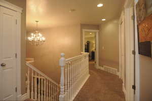 Hallway featuring carpet flooring and a chandelier