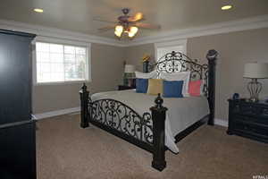 Carpeted bedroom featuring crown molding and ceiling fan