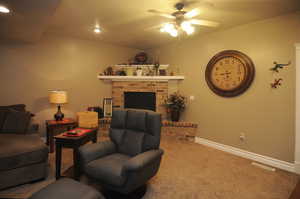 Carpeted living room with a brick fireplace and ceiling fan