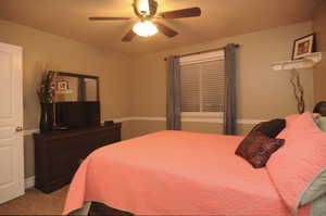 Carpeted bedroom featuring ceiling fan