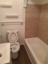 Bathroom featuring hardwood / wood-style flooring, tiled shower / bath combo, and toilet