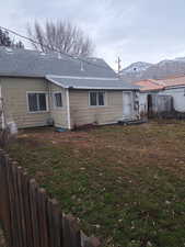 Rear view of house with a mountain view and a lawn