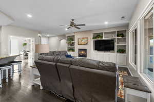 Living room featuring built in shelves, ceiling fan, dark hardwood / wood-style floors, and a wealth of natural light