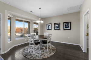 Dining room with dark wood-type flooring and a notable chandelier