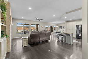 Living room with ceiling fan with notable chandelier, a textured ceiling, and dark hardwood / wood-style flooring