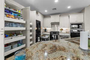 Kitchen with built in microwave, white cabinetry, oven, and stainless steel gas range oven