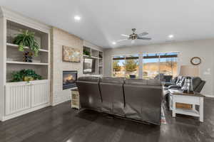 Living room featuring a mountain view, a stone fireplace, dark wood-type flooring, and built in features