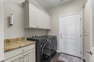 Laundry room featuring separate washer and dryer, dark hardwood / wood-style flooring, cabinets, and a textured ceiling