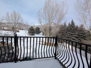 Snow covered back of property featuring a mountain and golf course view