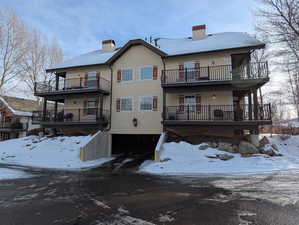 Snow covered rear of property featuring a balcony