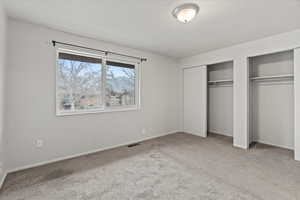 Unfurnished bedroom with two closets and carpet